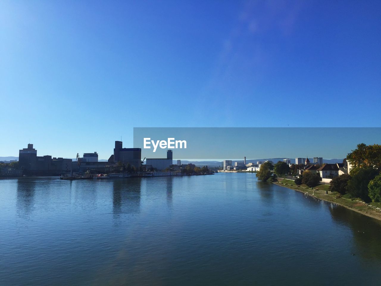 BUILDINGS BY RIVER AGAINST BLUE SKY