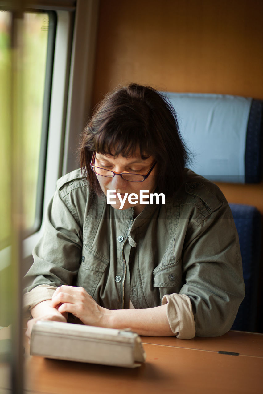 Mature woman using digital tablet in train