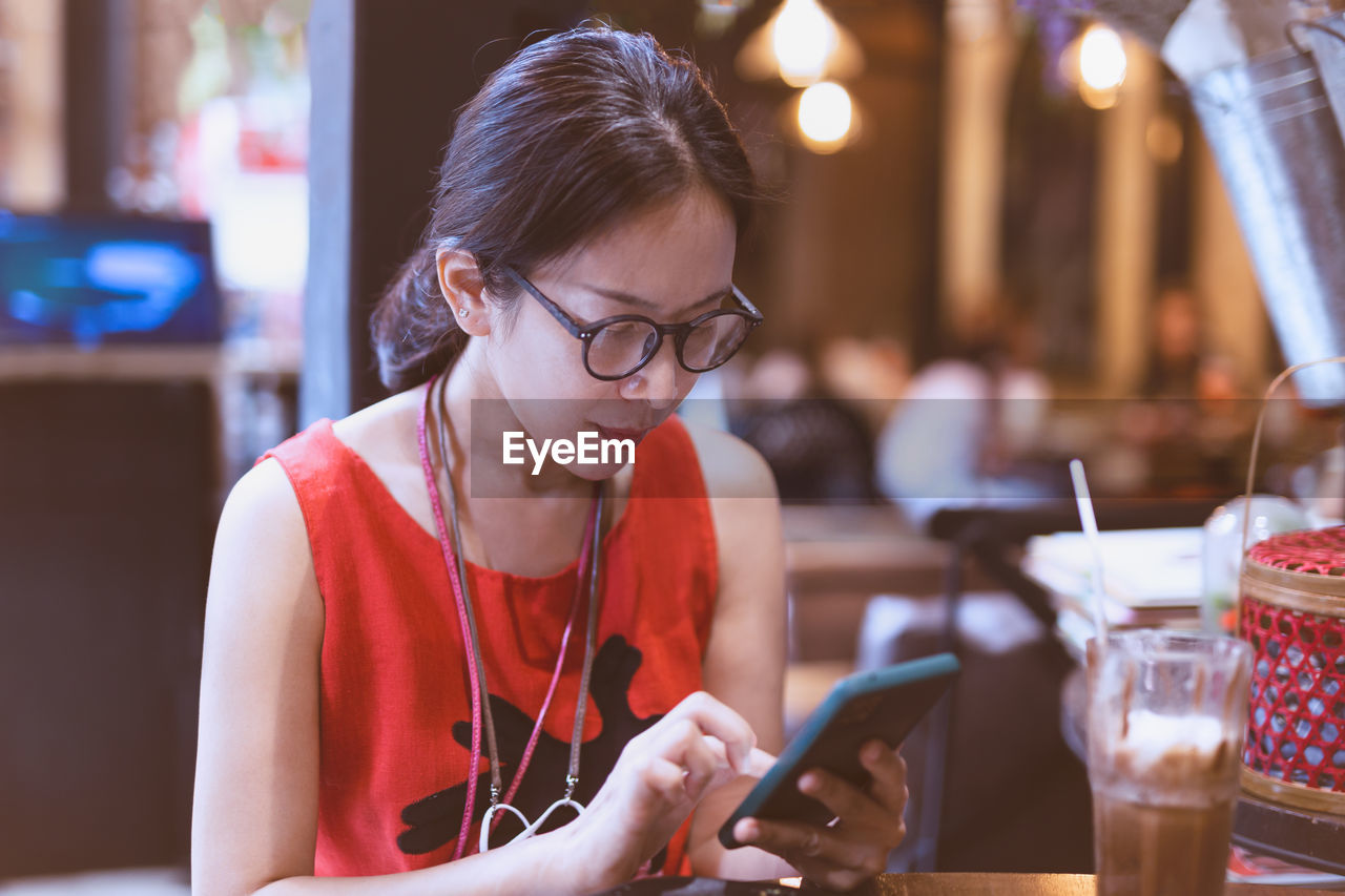 Woman using phone while sitting in restaurant