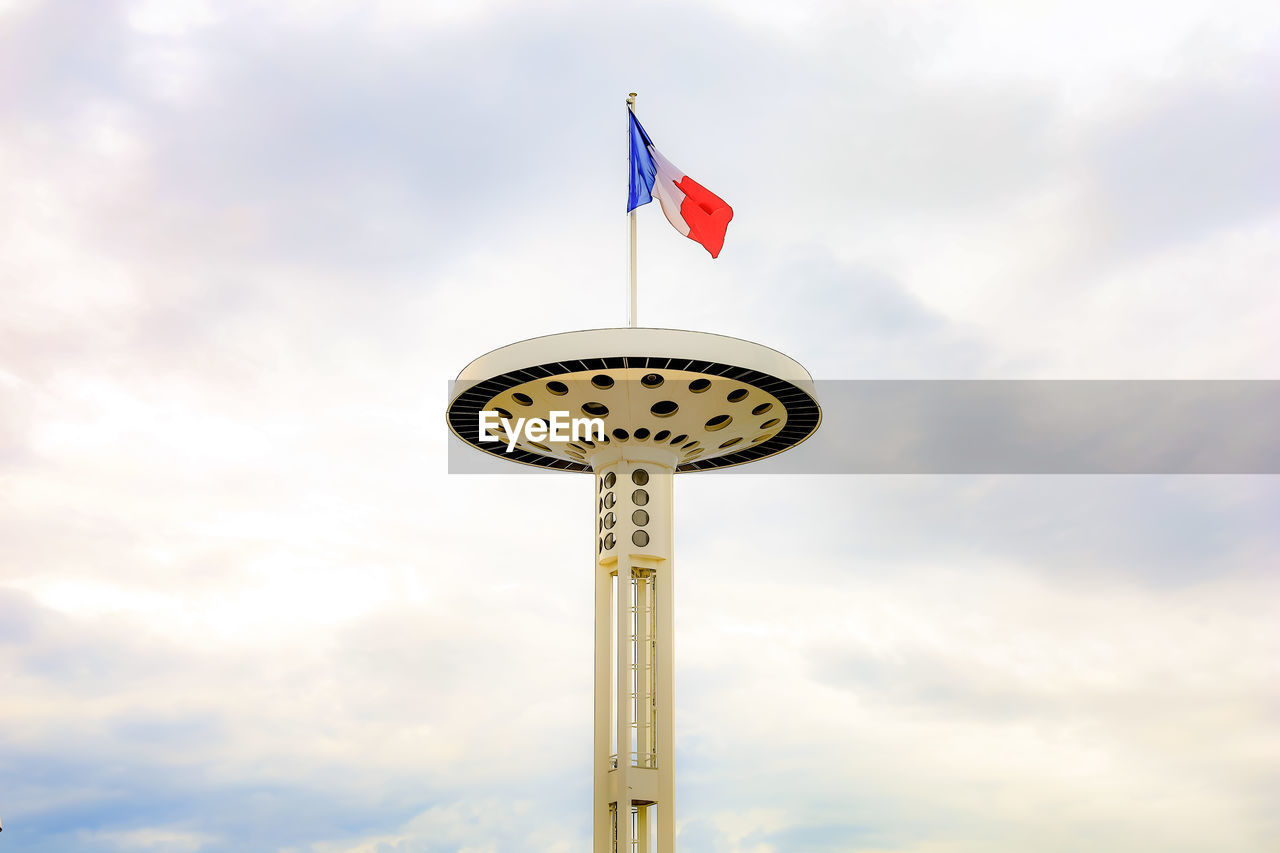 Low angle view of a building with a franch flag against sky