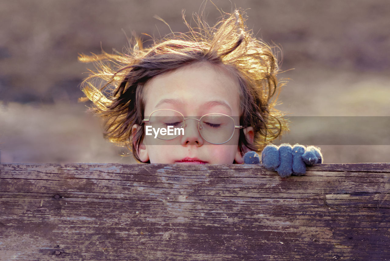 Close-up of cute boy wearing eyeglasses on wood