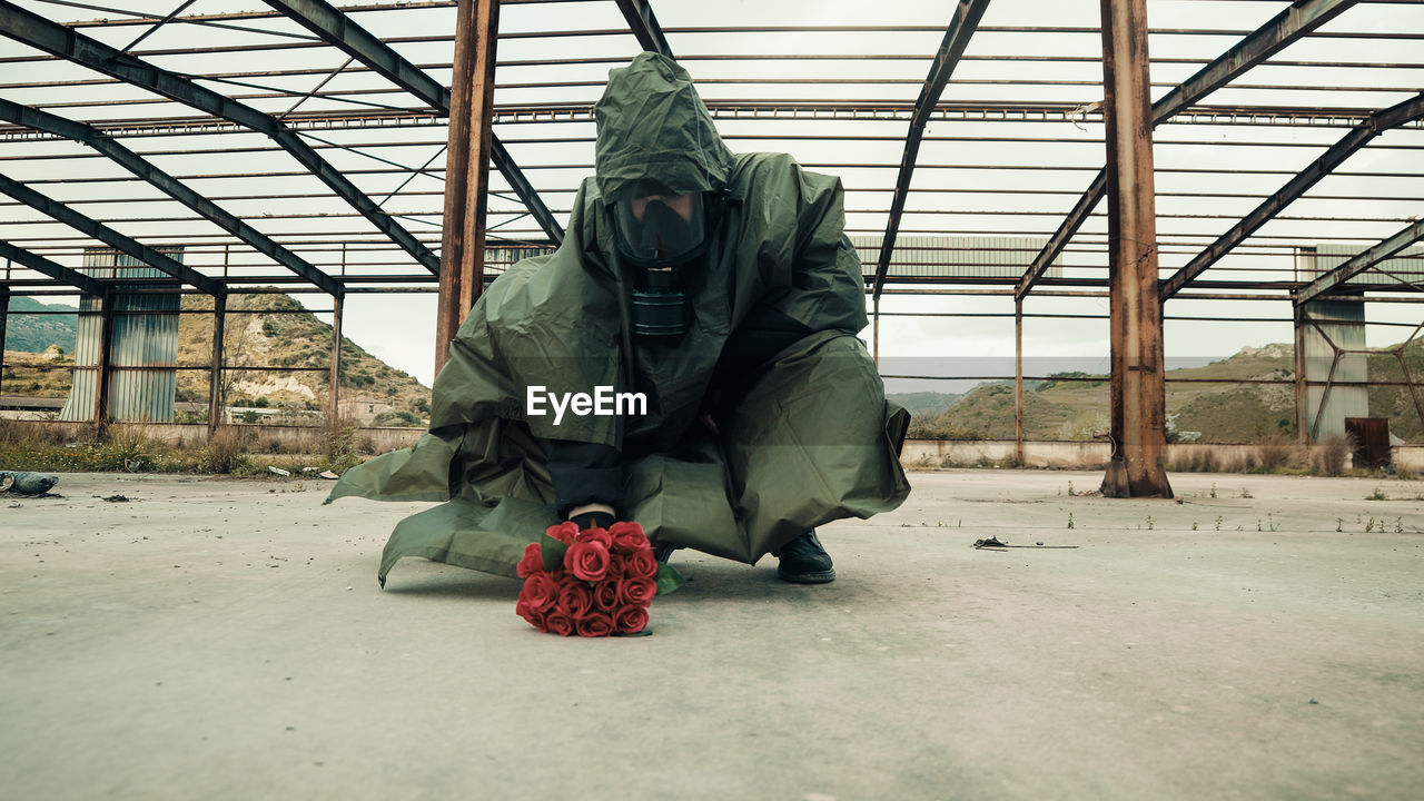 Soldier leans bunch of red flowers on the ground