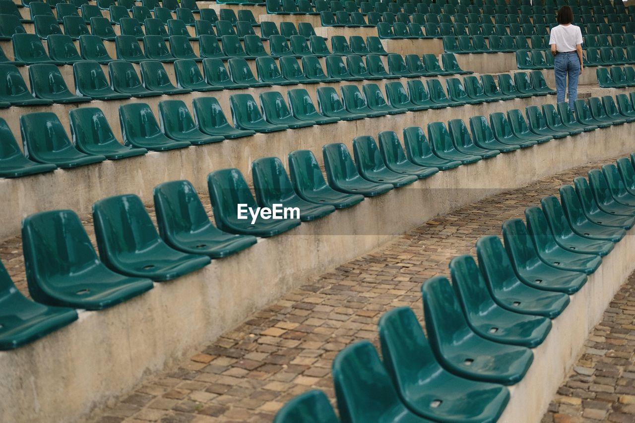 Rear view of woman standing by bleachers at stadium