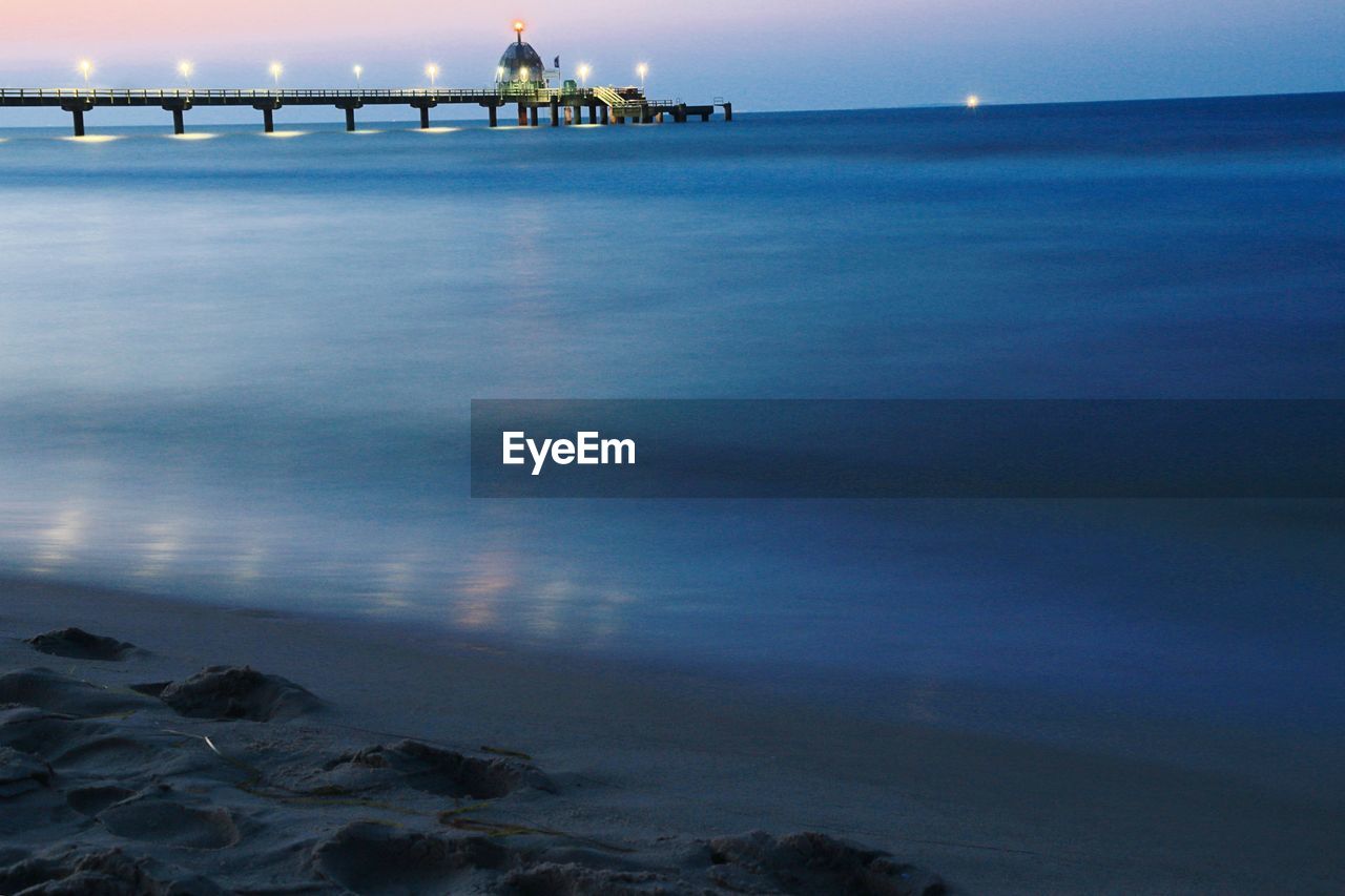 Illuminated pier in baltic sea against sky