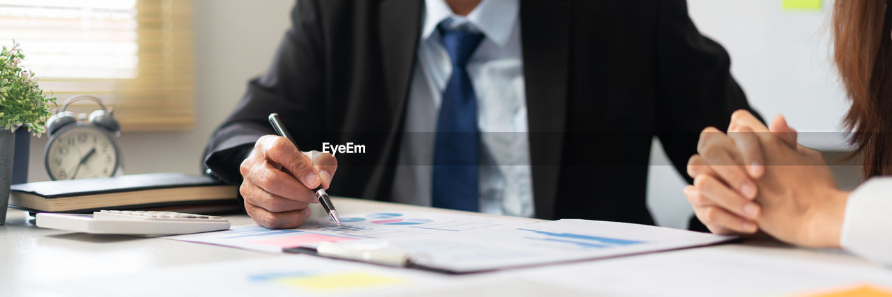 midsection of business colleagues working on table