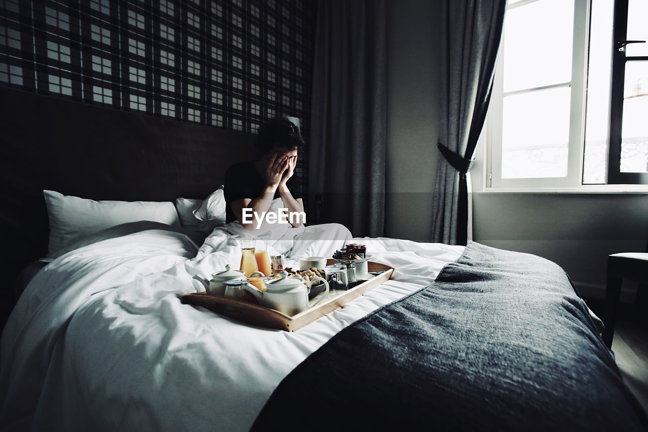 YOUNG WOMAN SITTING ON BED