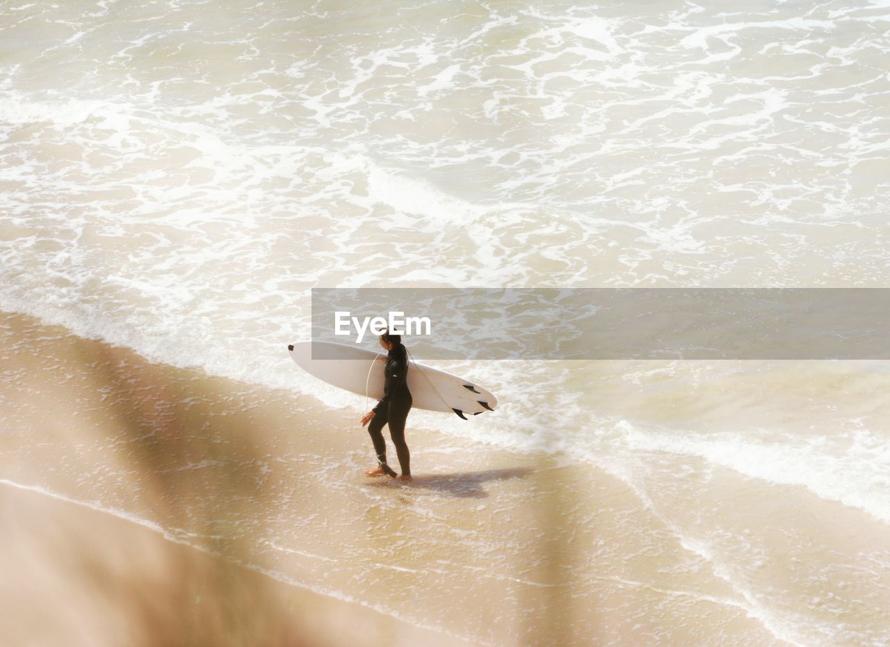 HIGH ANGLE VIEW OF WOMAN STANDING IN WATER