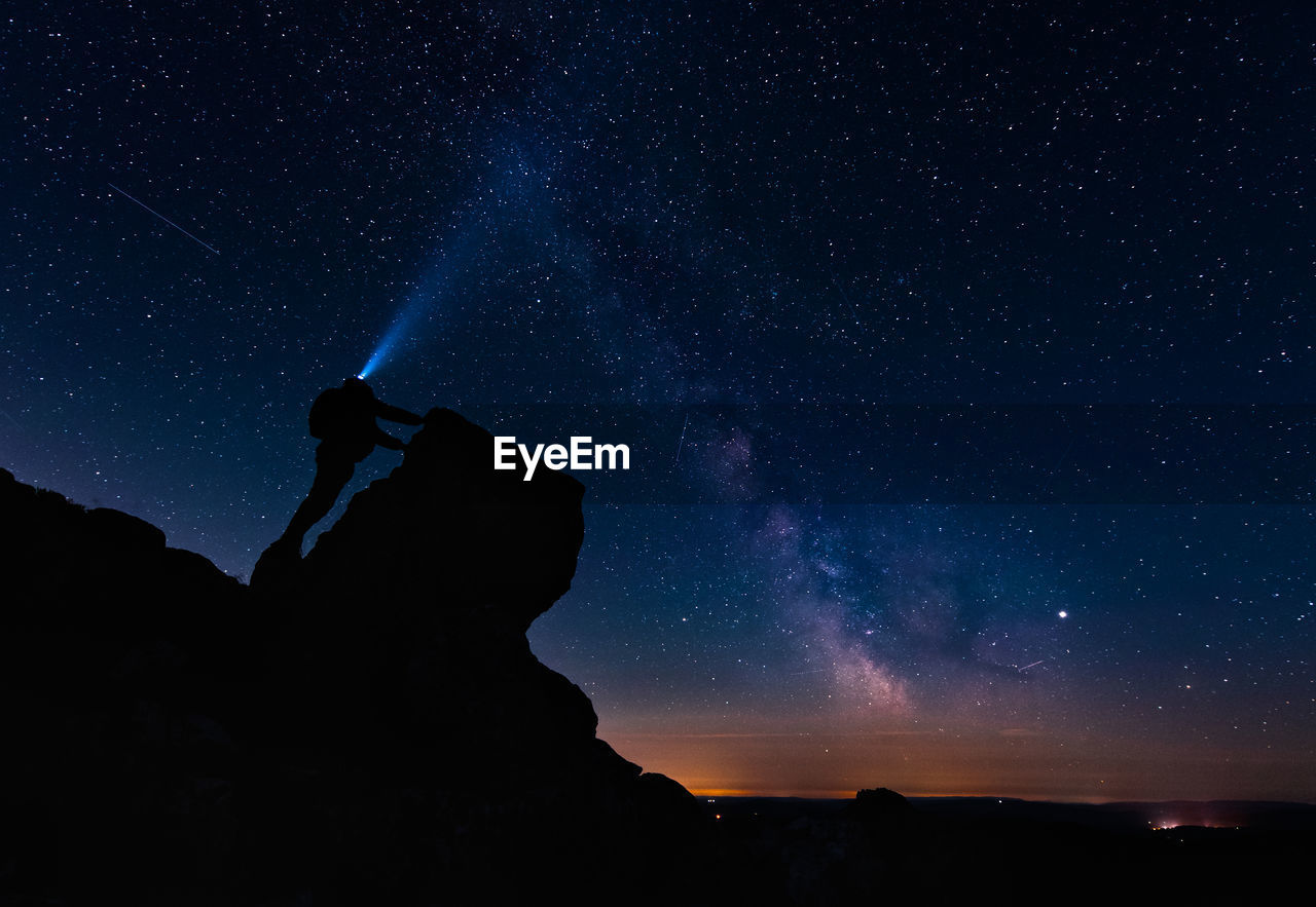 Silhouette man standing against star field at night