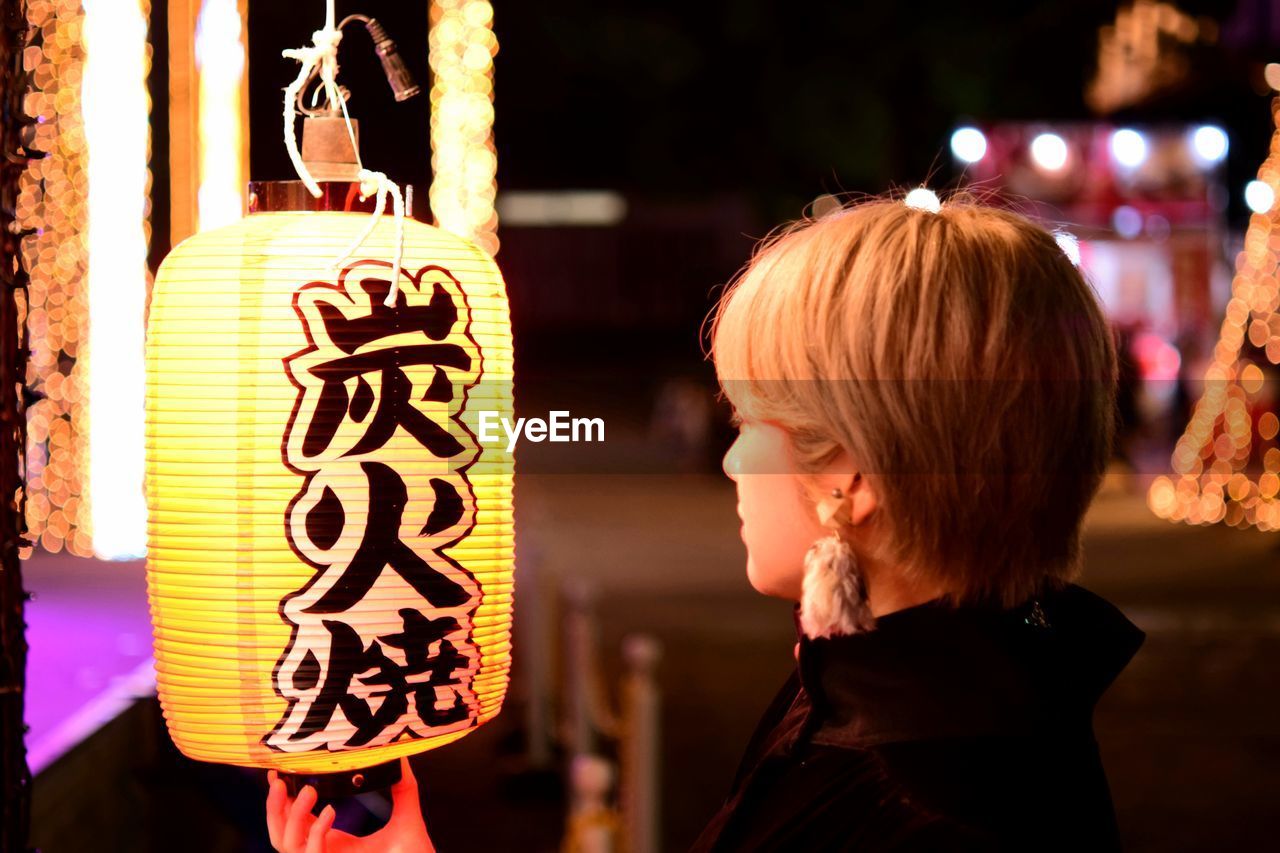 Side view of woman with illuminated text at night