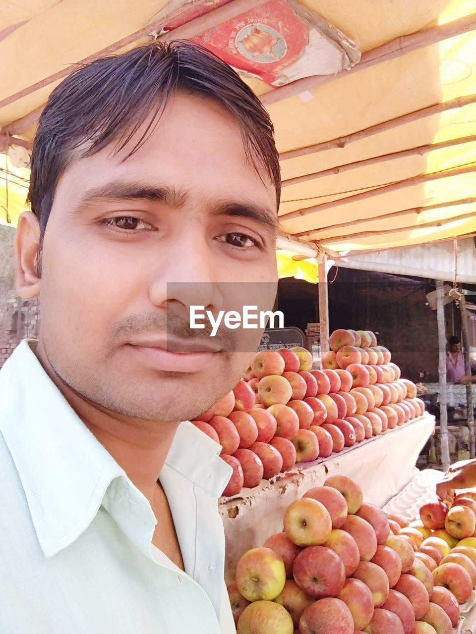 Portrait of young man with orange fruits at market stall