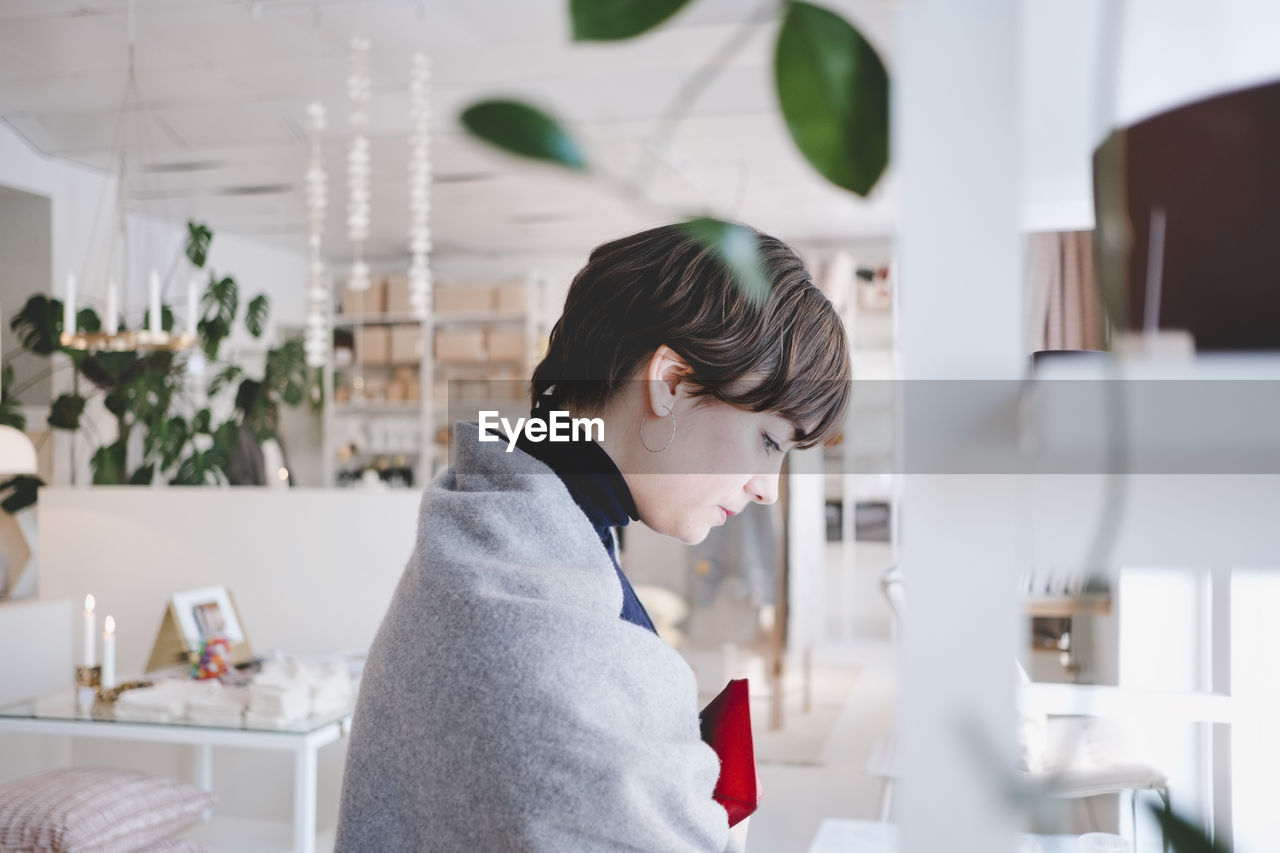 Side view of young female customer shopping in store