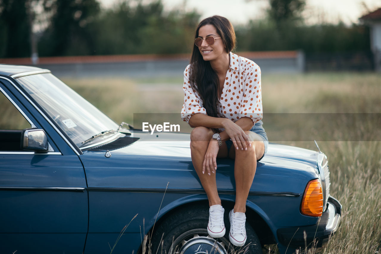 Smiling woman sitting on the car