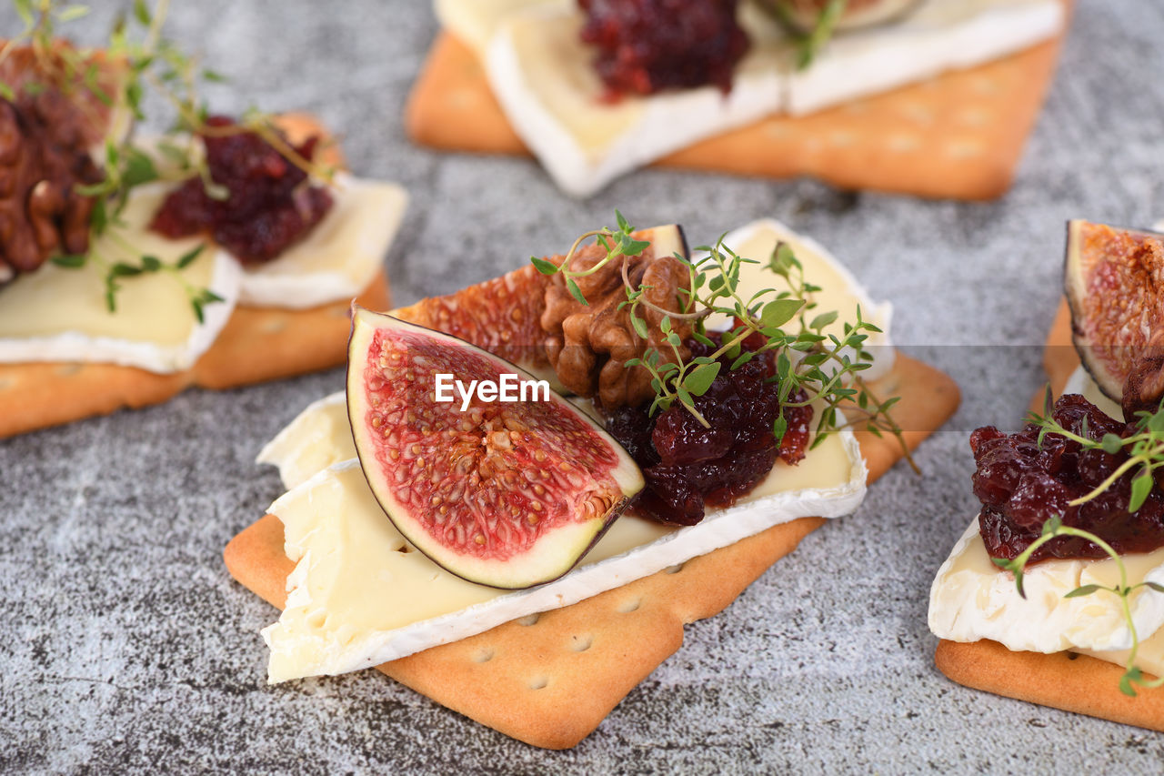 Cracker with a slice of camembert, jam, figs and nuts. a snack idea for a holiday, picnic or party.