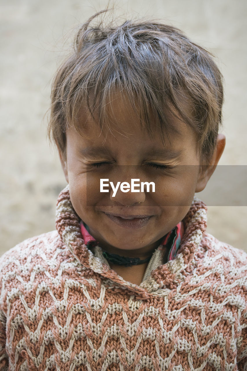 Close-up of smiling boy with eyes closed wearing warm clothing outdoors