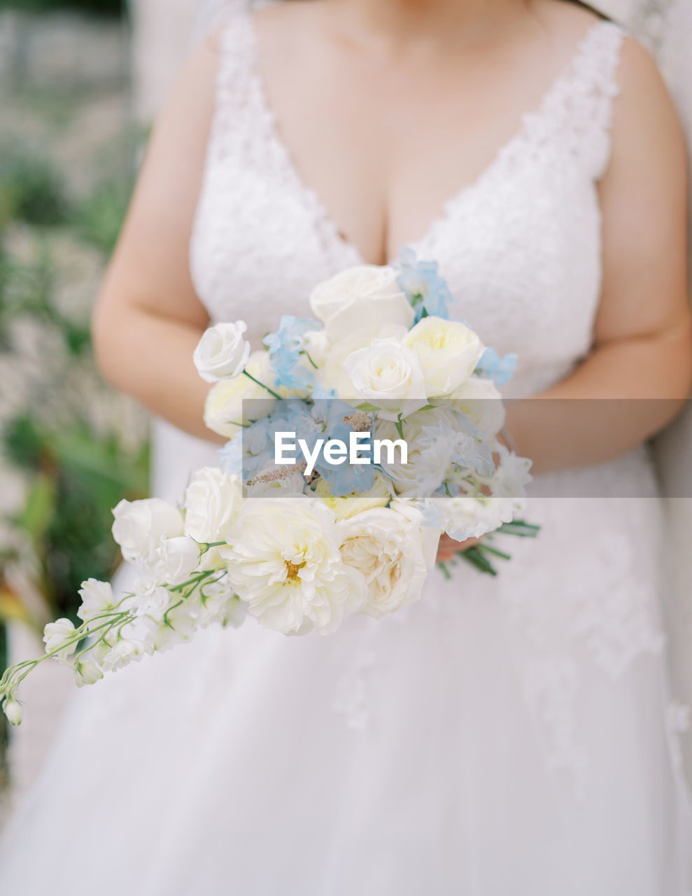 midsection of bride with bouquet