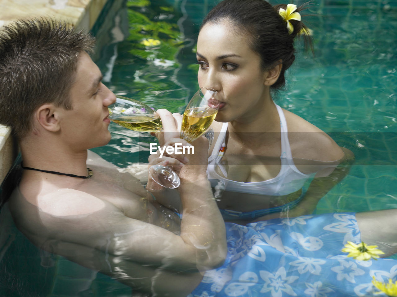 Close-up of couple having drink in swimming pool