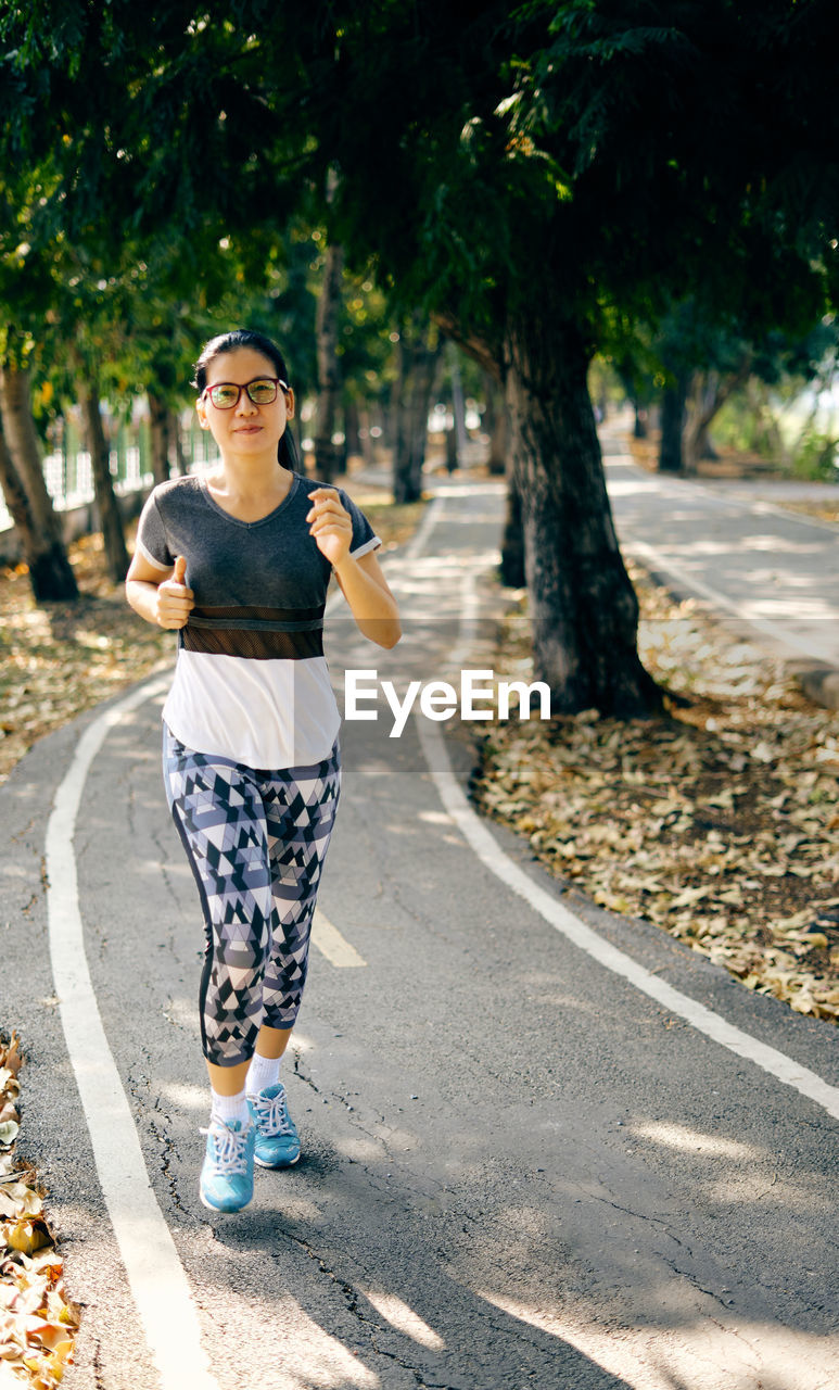 Woman doing yoga on road against trees