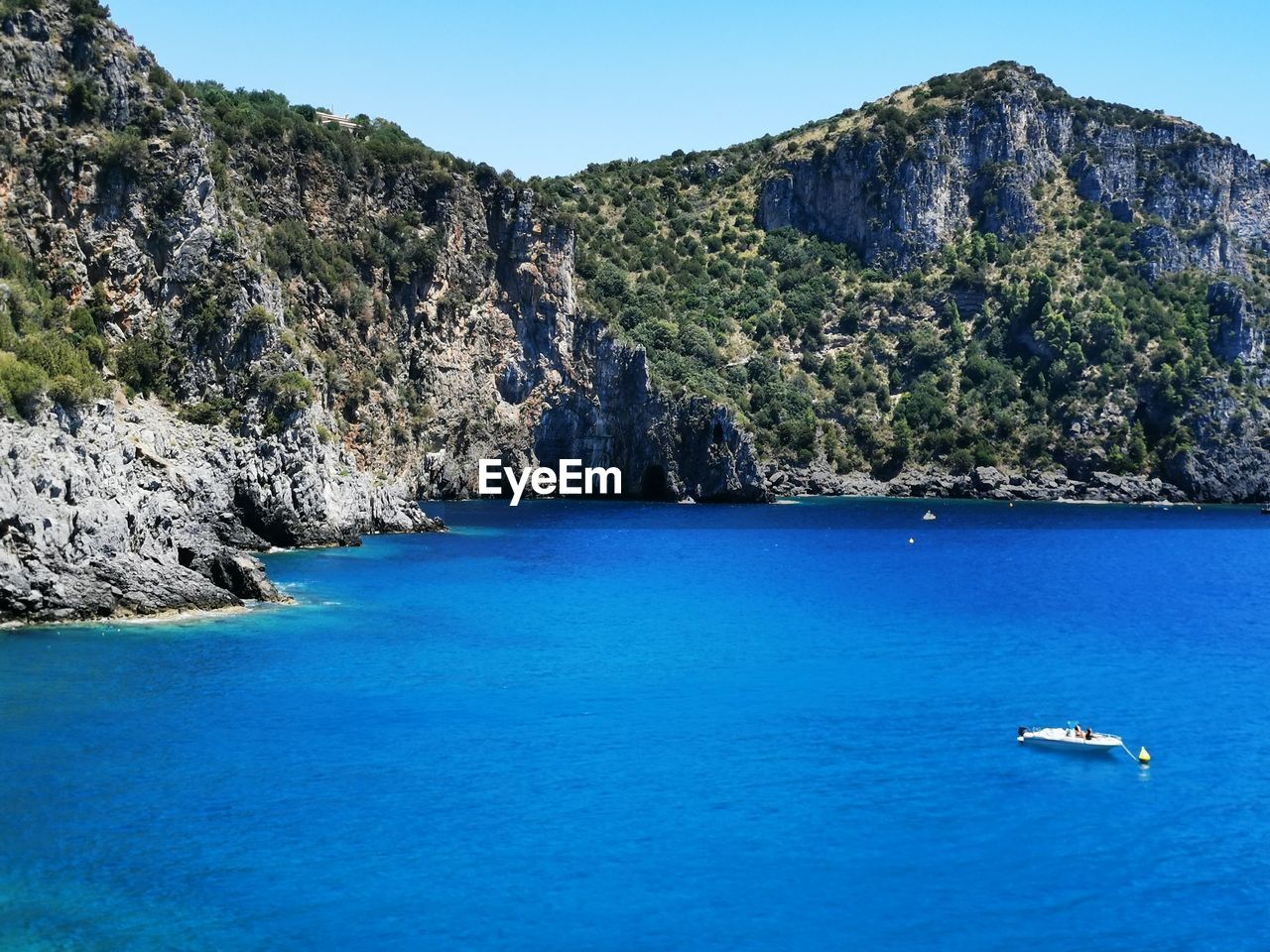 Scenic view of sea and mountains against blue sky