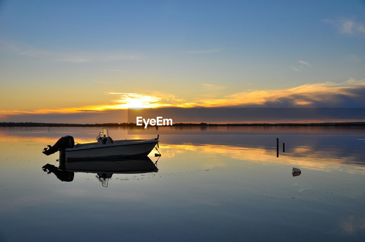 Boat in lake against sky during sunset