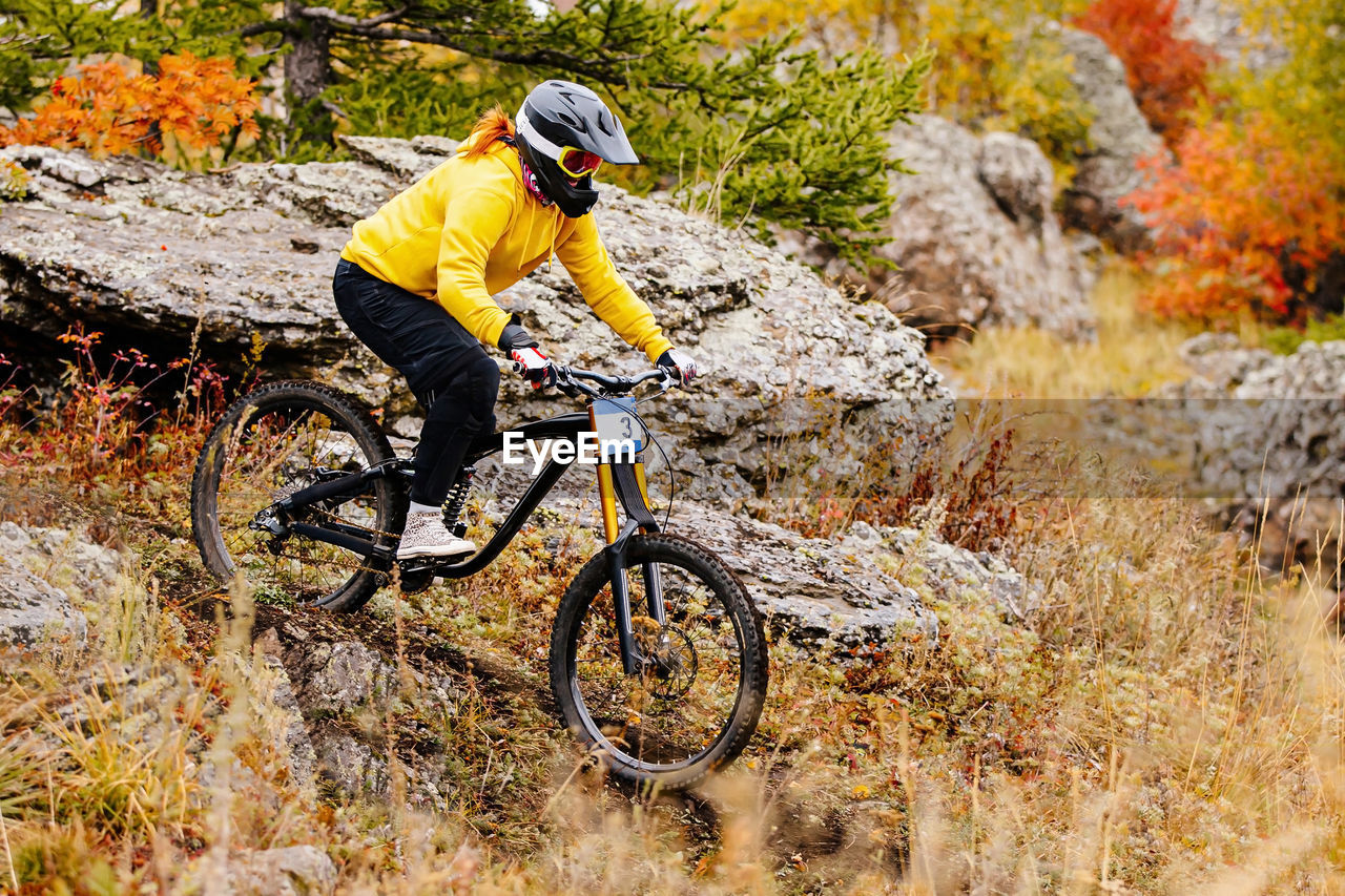 Woman rider riding on autumn trail in downhill race