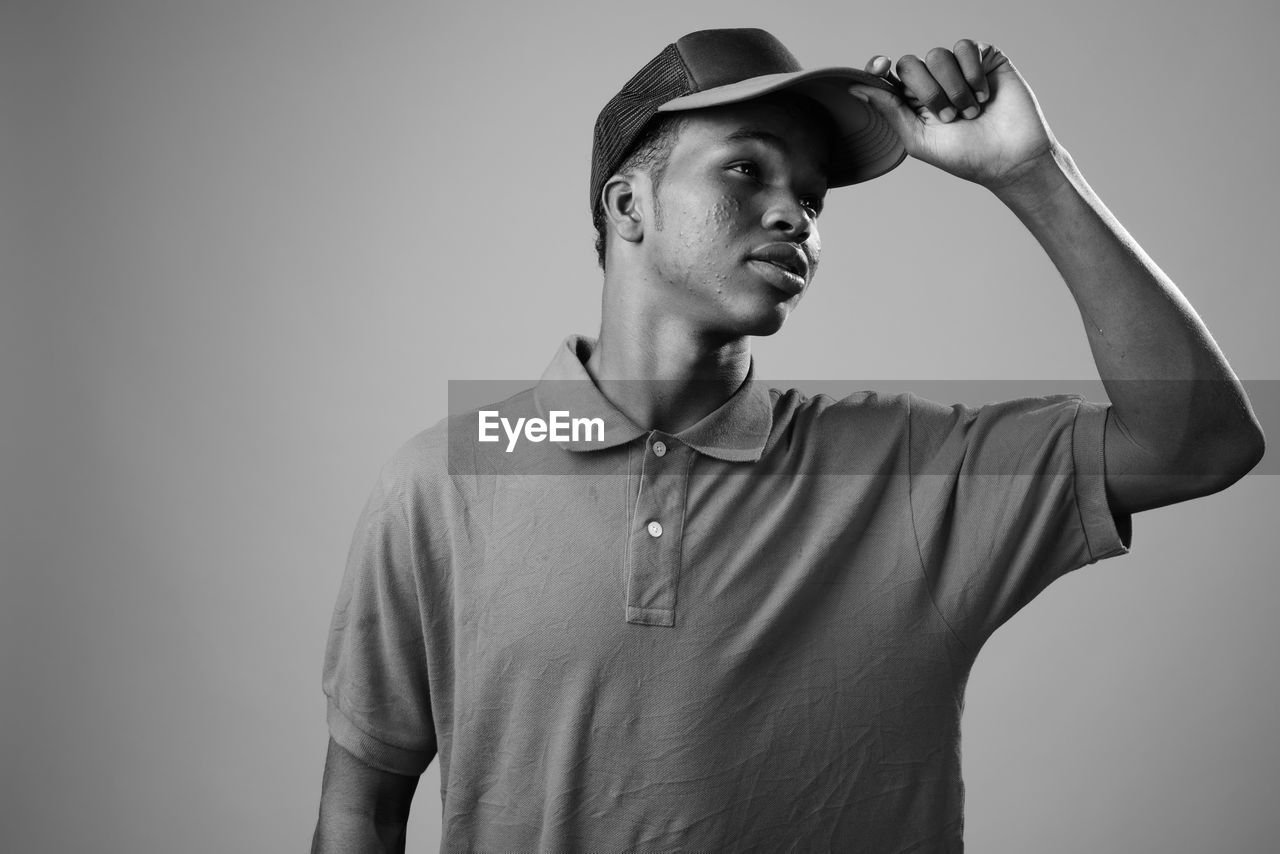 PORTRAIT OF YOUNG MAN LOOKING AWAY AGAINST WALL