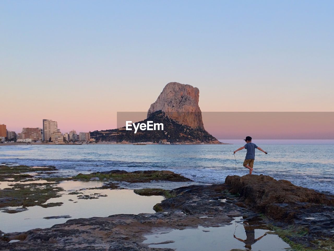 Rear view of a boy overlooking calm sea