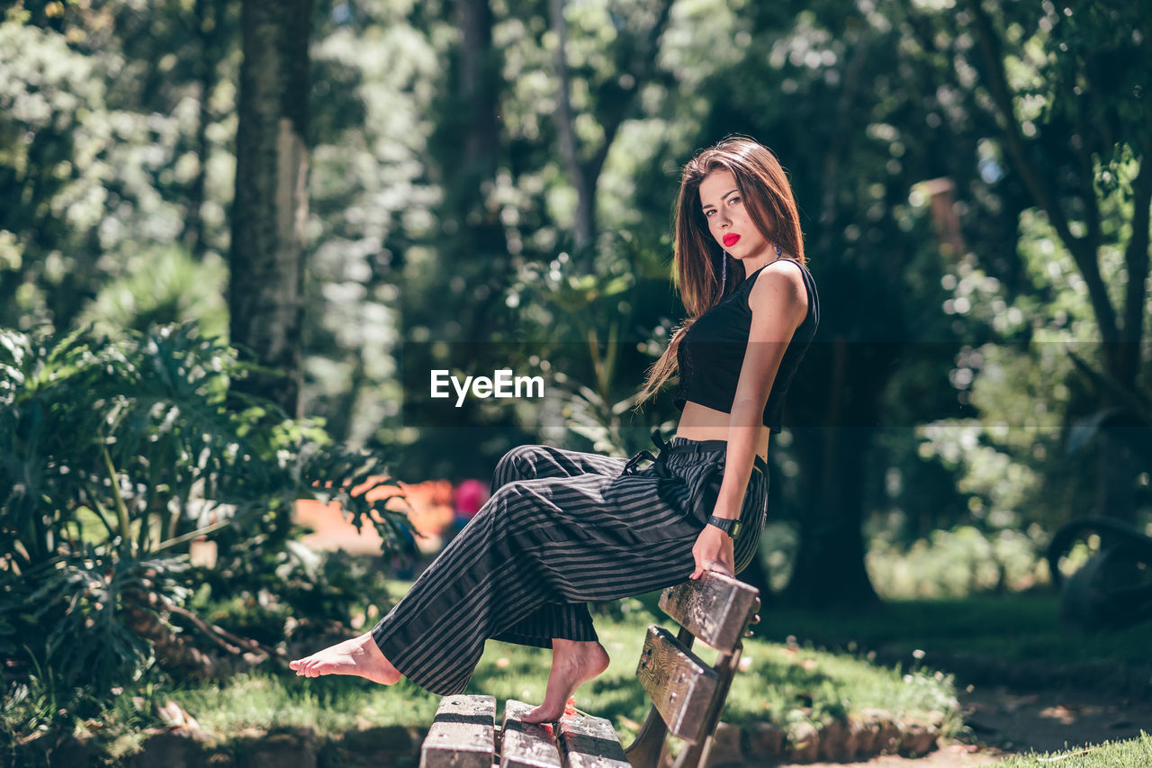 Portrait of woman sitting on bench in park