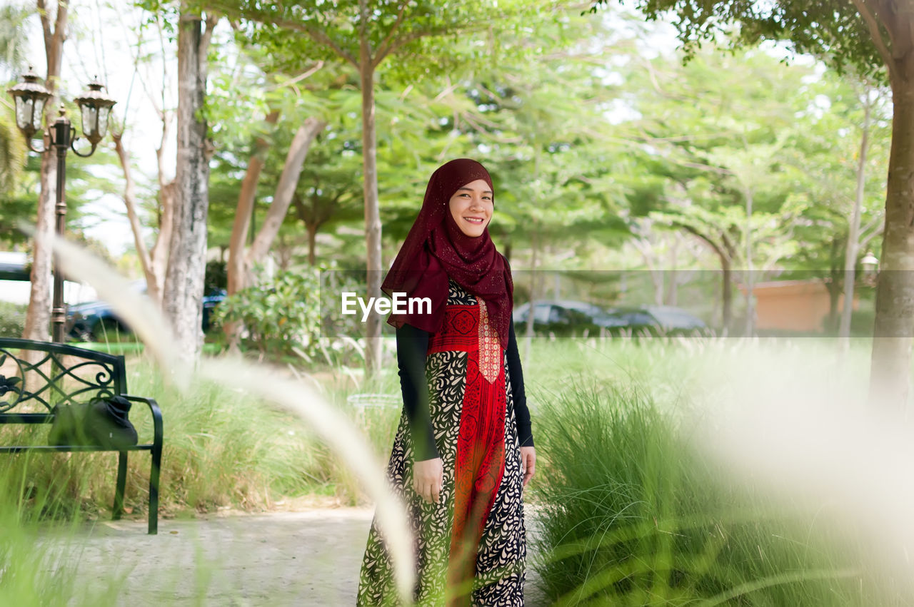 Portrait of smiling woman against trees