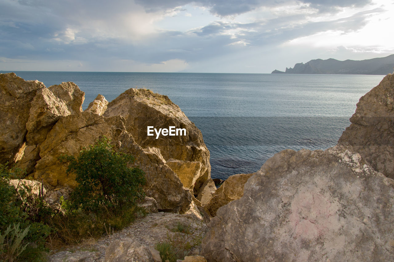 Rocks on shore by sea against sky