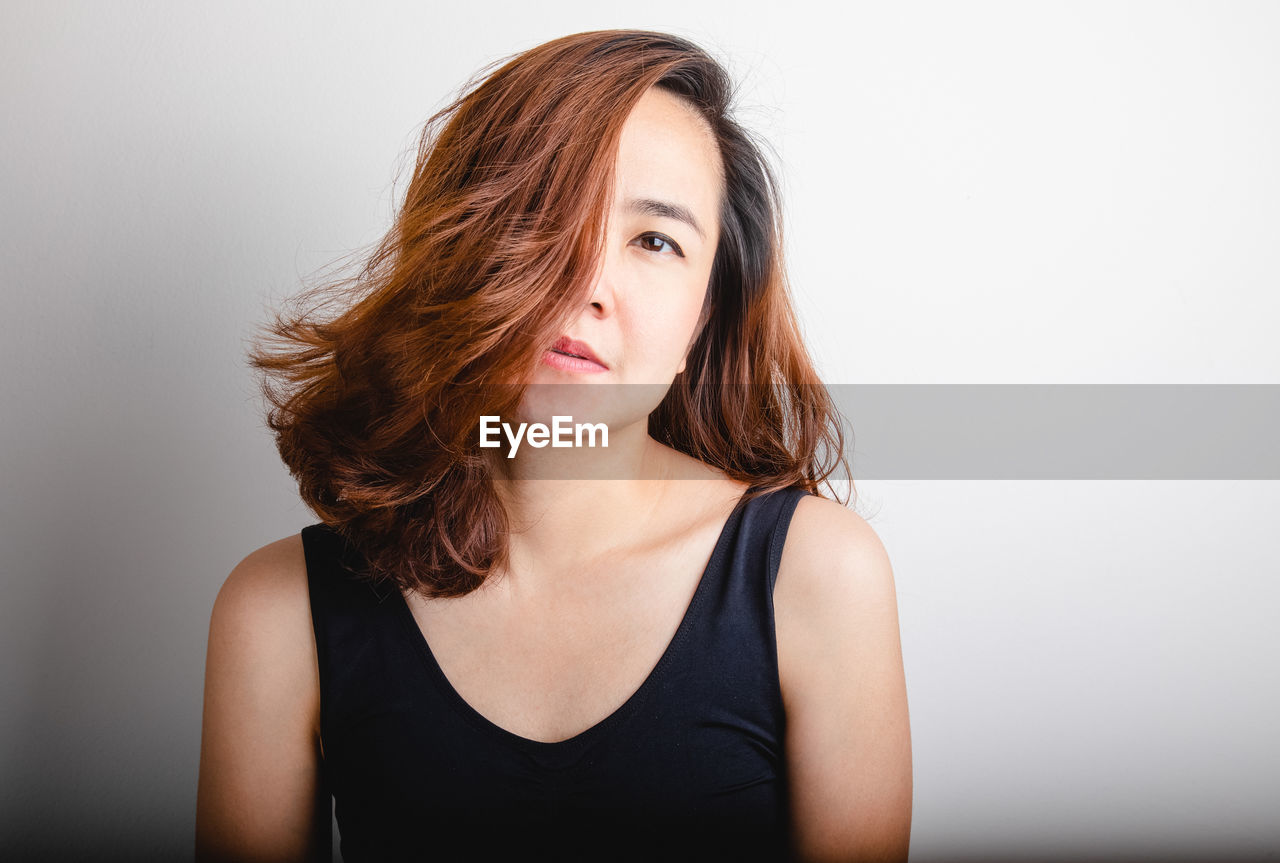 PORTRAIT OF BEAUTIFUL WOMAN AGAINST WHITE BACKGROUND