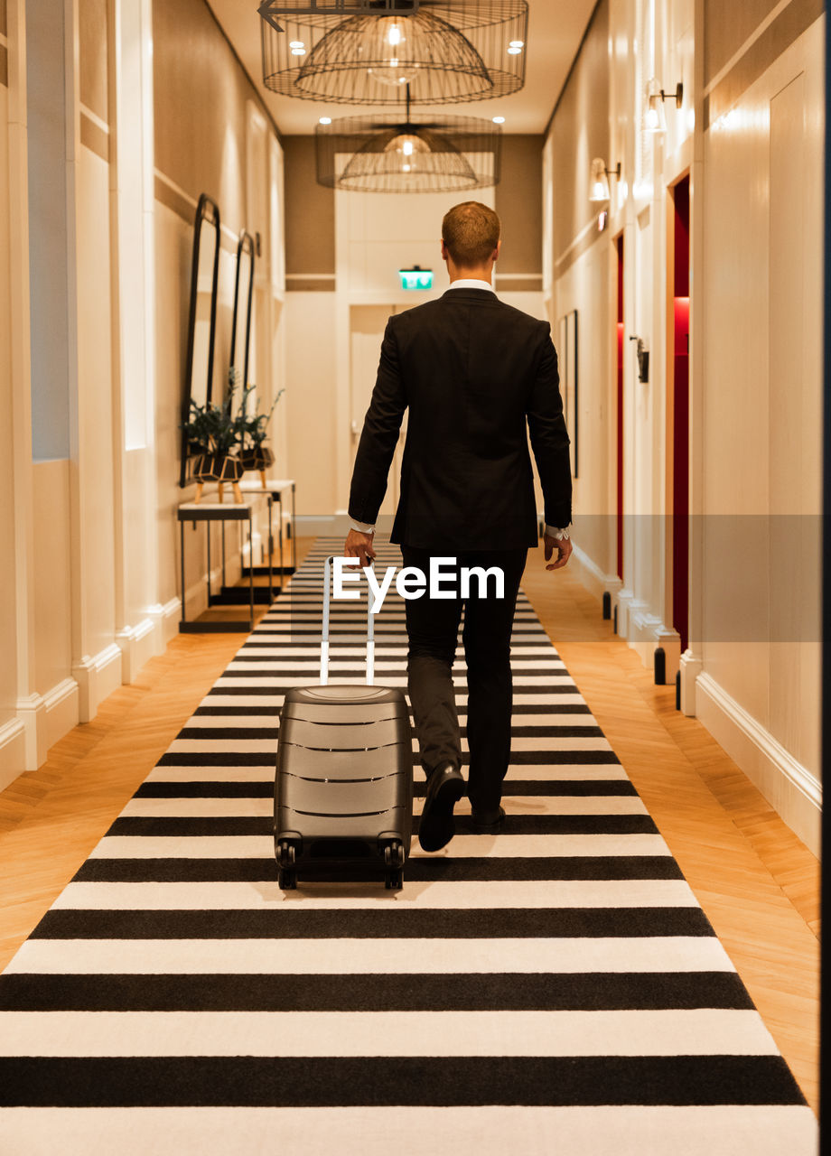 Anonymous businessman walking on striped carpet in hotel