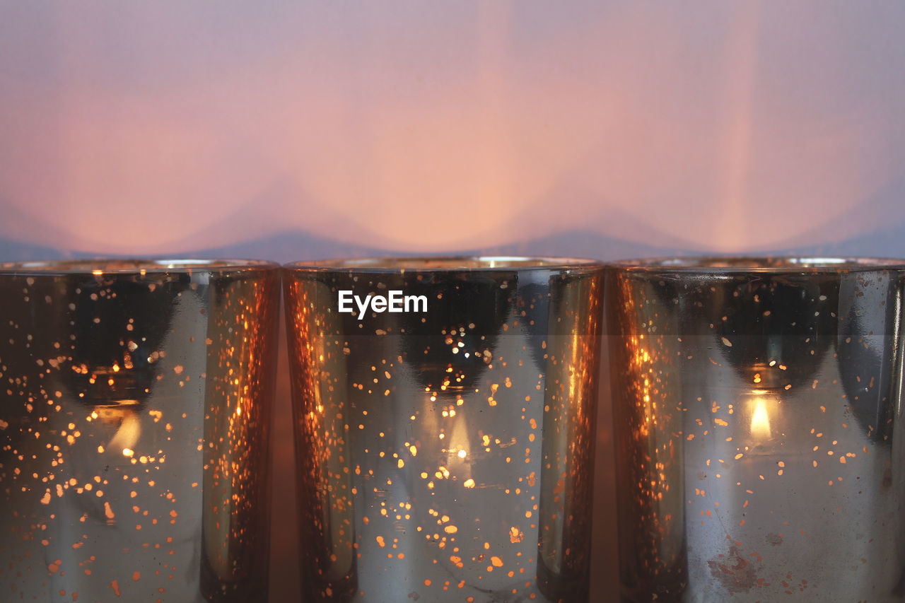 Close-up of lit tea light candle against wall