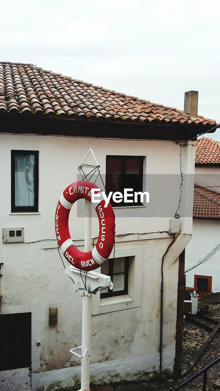 ROAD SIGNS IN FRONT OF HOUSE AGAINST SKY