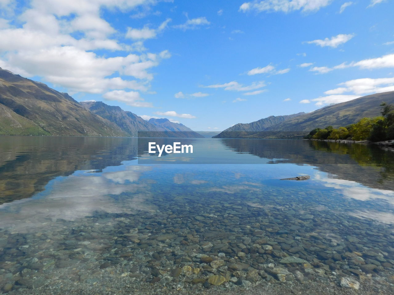 Scenic view of lake and mountains against blue sky