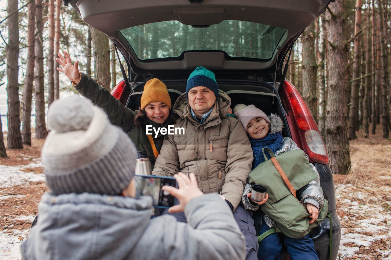 Winter family road trip. happy parents with kids make photo in the trunk of car during walking