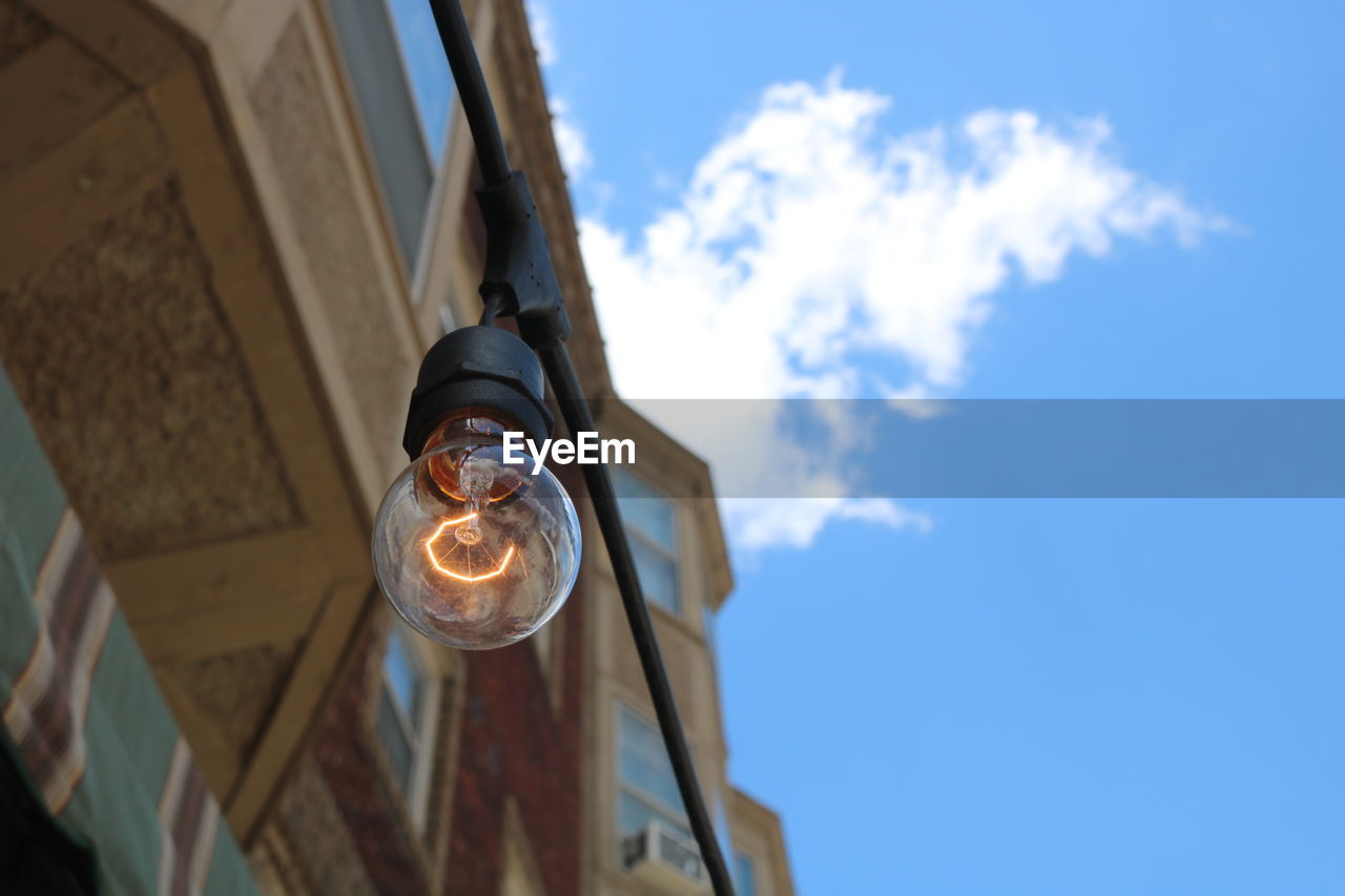 Low angle view of illuminated light bulb against sky