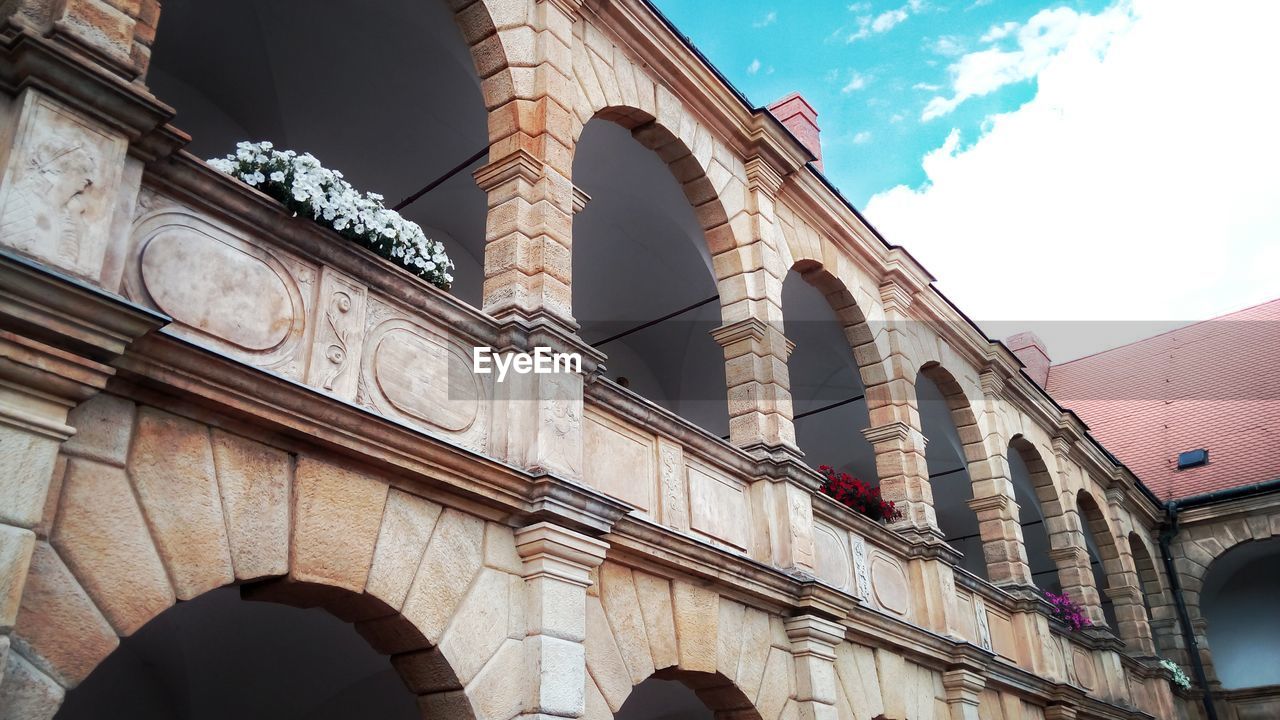 Low angle view of window boxes on old building against sky