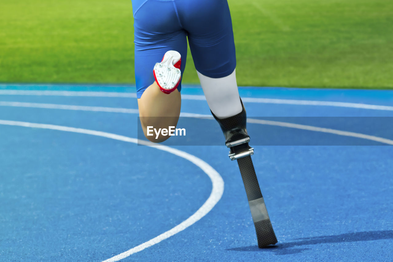 Low section of athlete running with prosthetic leg on track