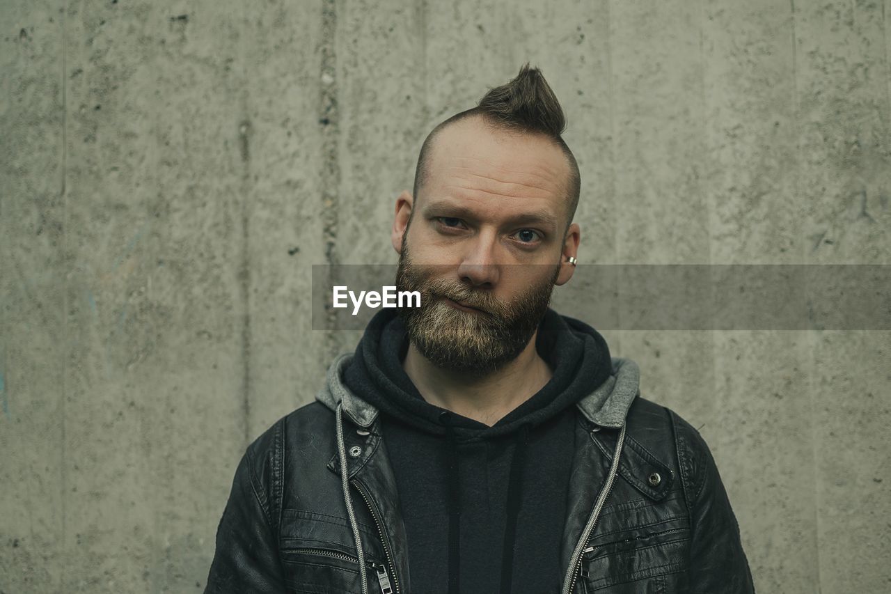 Portrait of man with spiky hair making face against wall