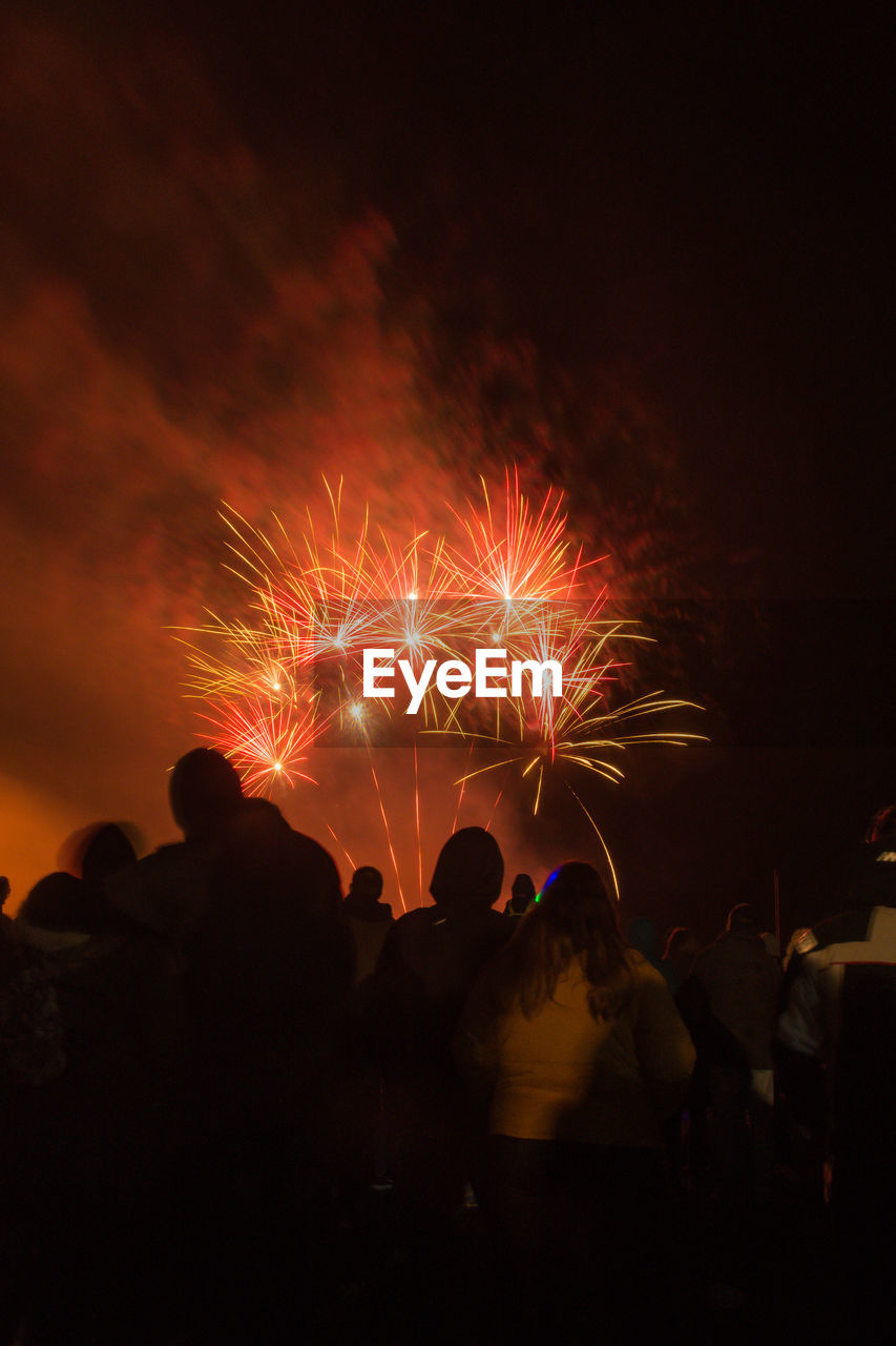 Silhouette people watching firework display at night