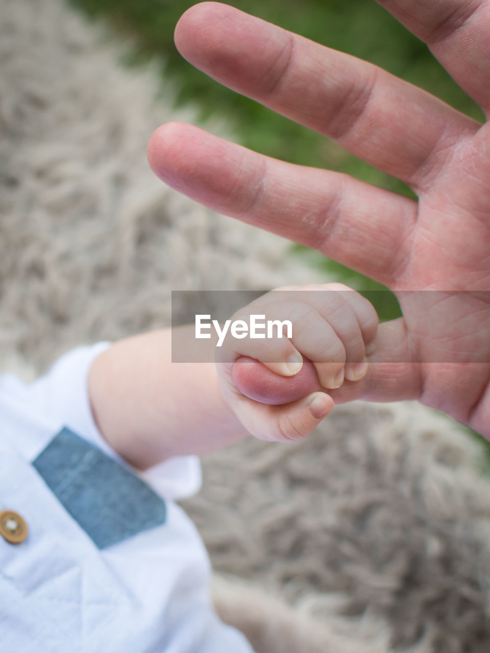 Close up photo of a small baby holding an adult male pinky finger