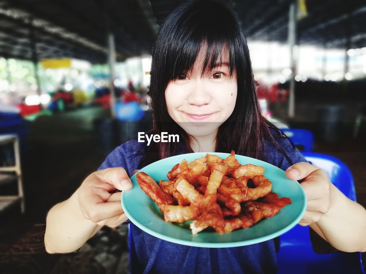 Portrait of smiling young woman holding food in plate at restaurant