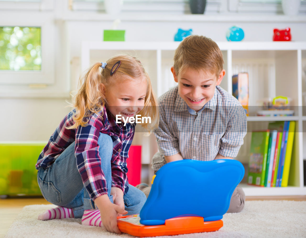 Cute sibling playing with toy while sitting at home