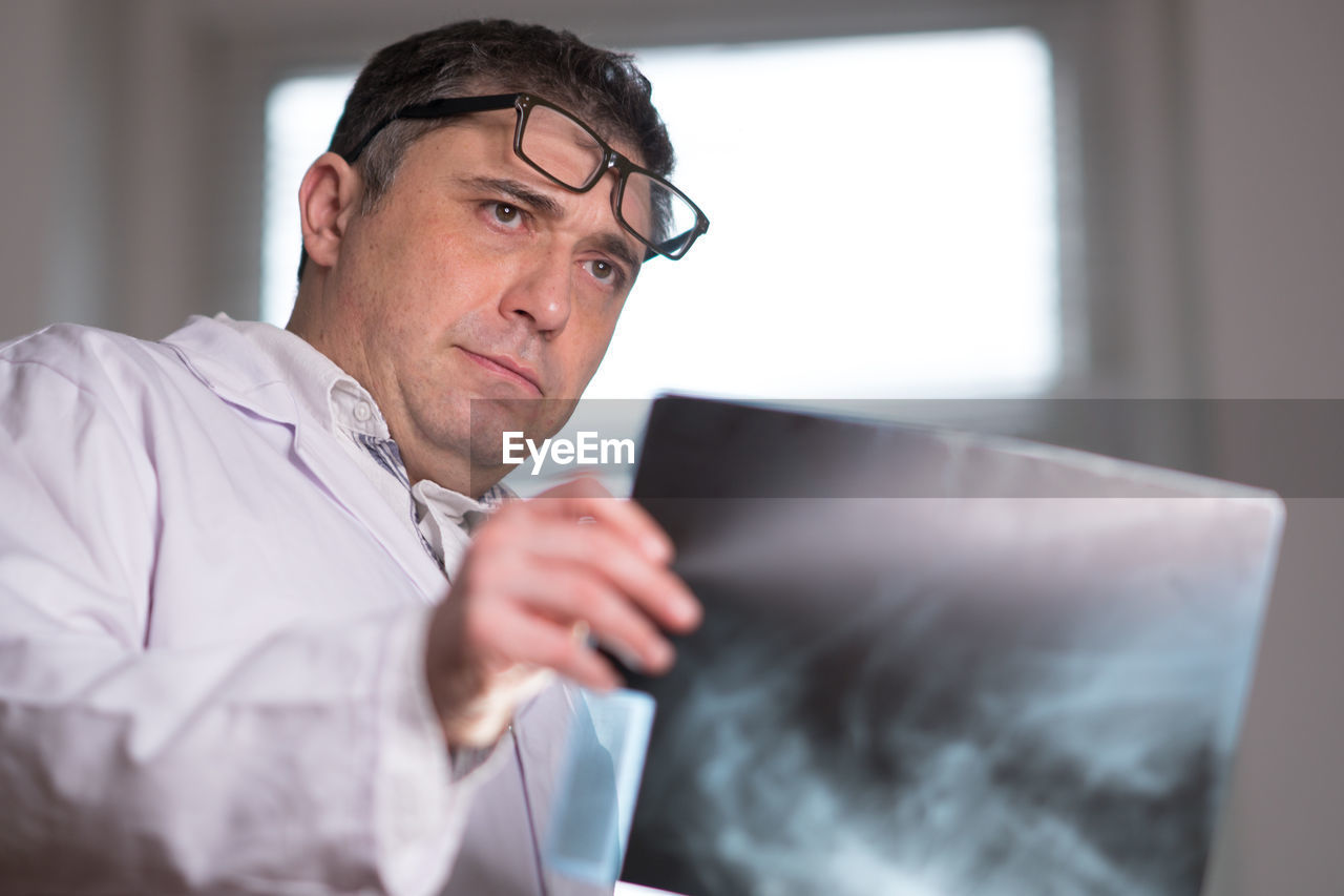 CLOSE-UP OF MAN USING MOBILE PHONE IN OFFICE