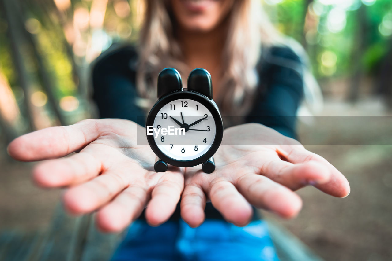 Close-up of woman holding clock