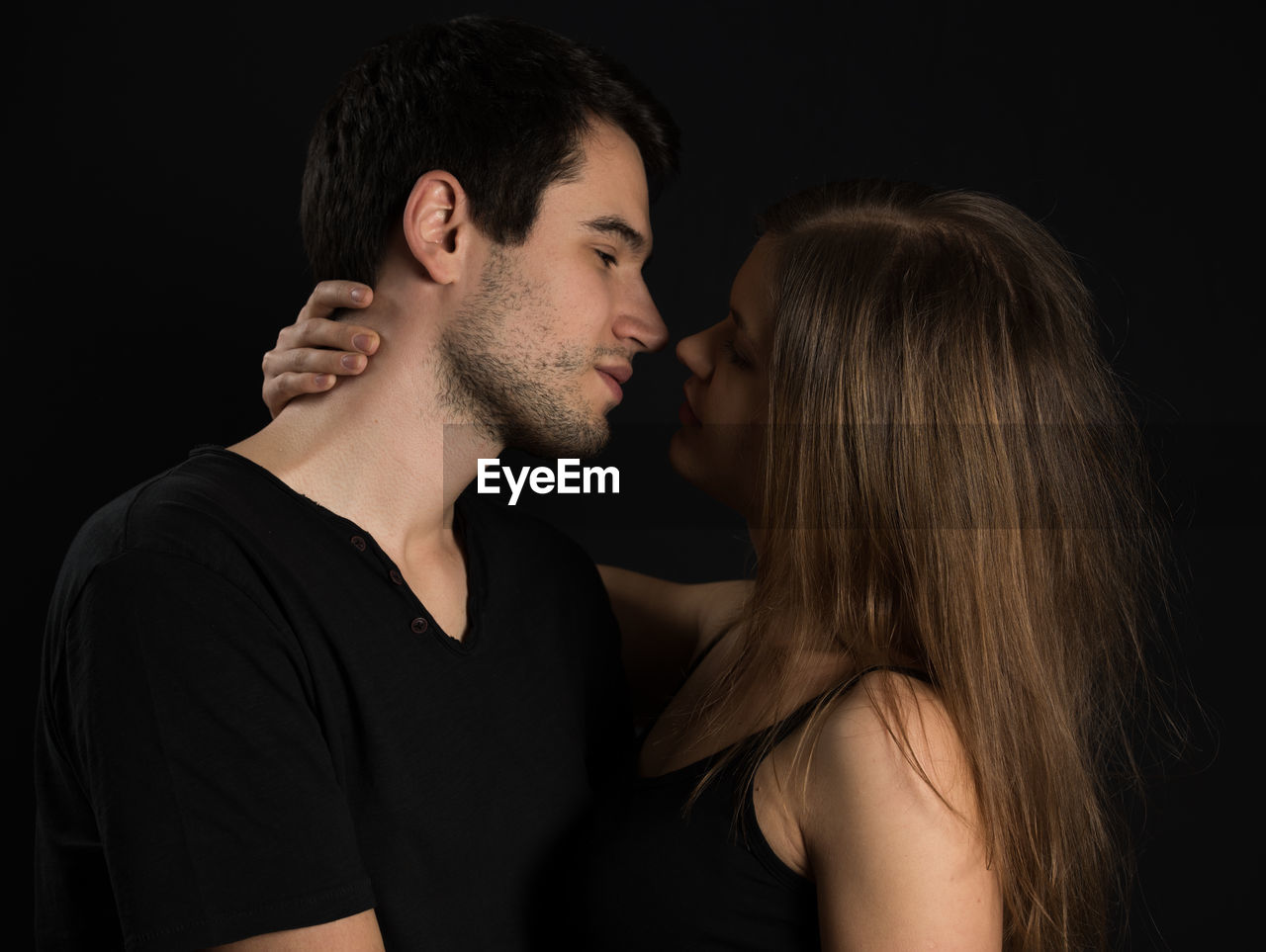 Young couple kissing against black background