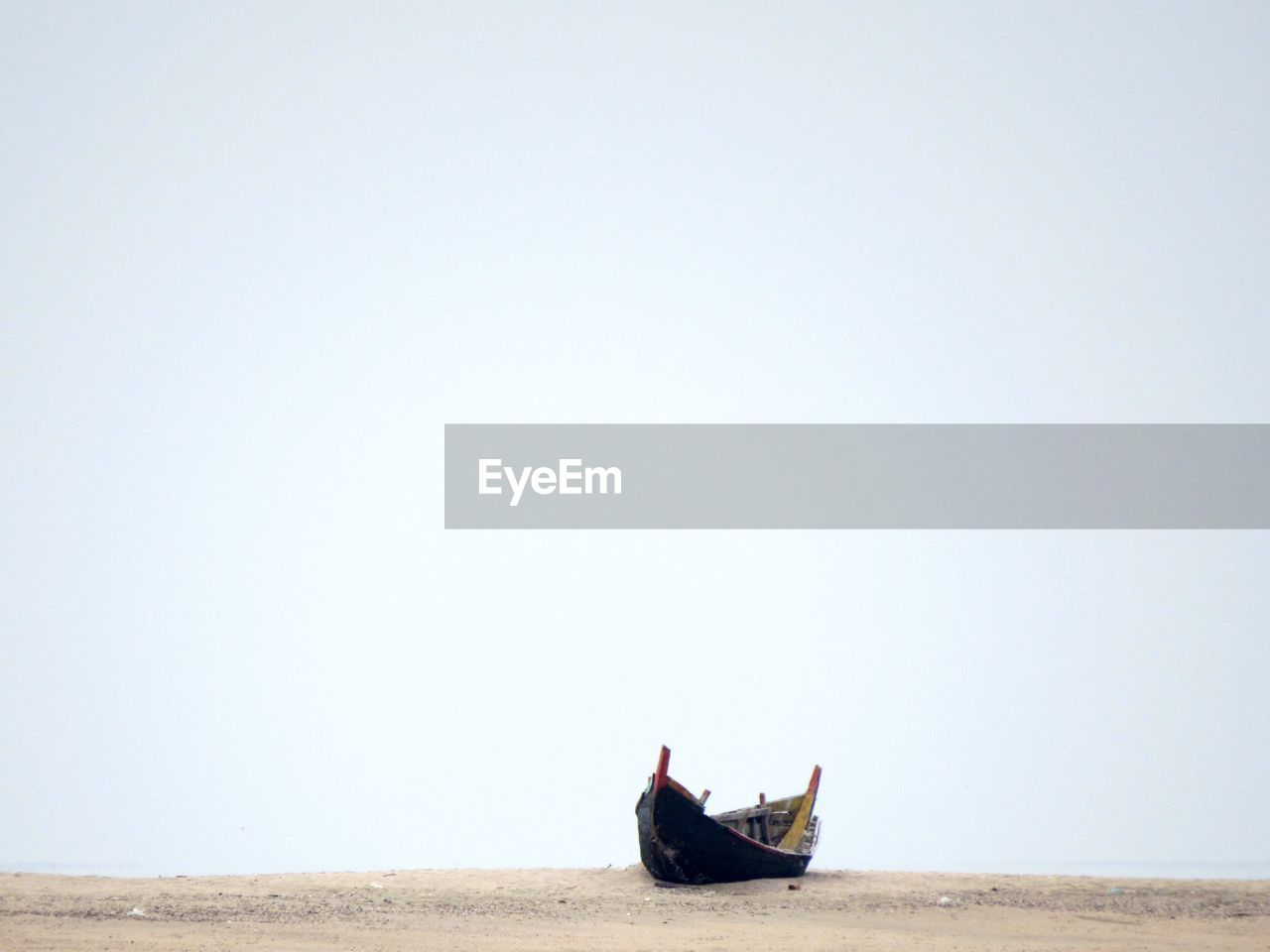 Abandoned boat on shore against clear sky