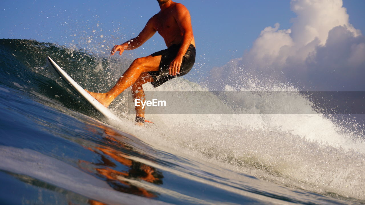 Man surfing in sea against sky