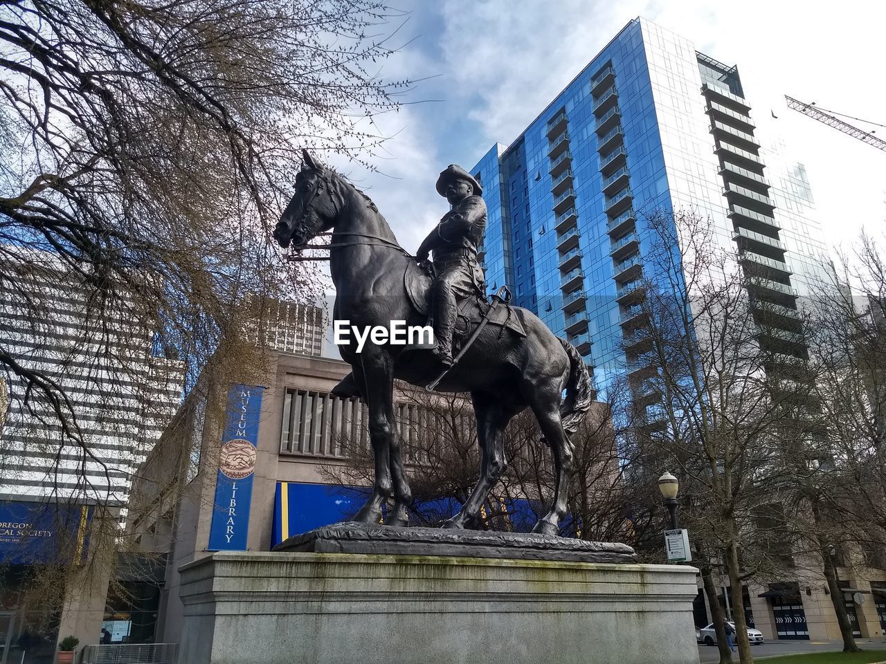 LOW ANGLE VIEW OF STATUE AGAINST CITY