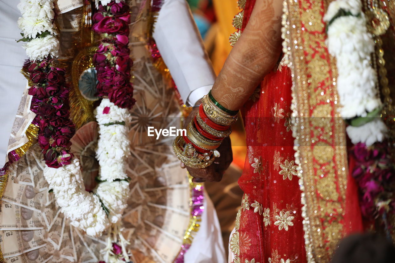 Midsection of bridal couple holding hands during wedding ceremony